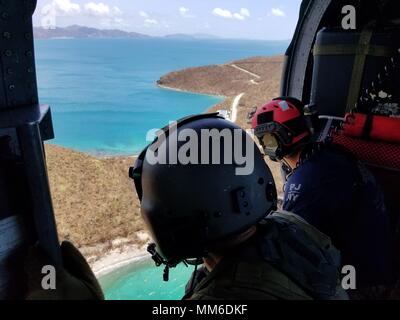 L'enquête sur la destruction de l'équipage de l'hélicoptère au-dessus des îles Vierges américaines. Aviateurs de la New York Air National Guard's 106th Rescue Wing voler plus de Saint-Thomas et Saint-John dans un HH-60 Pave Hawk helicopter le 10 septembre, 2017. Ils cherchent des personnes qui ont besoin d'une aide indispensable à la suite de l'ouragan l'Irma. Banque D'Images