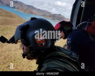 L'enquête sur la destruction de l'équipage de l'hélicoptère au-dessus des îles Vierges américaines. Aviateurs de la New York Air National Guard's 106th Rescue Wing voler plus de Saint-Thomas et Saint-John dans un HH-60 Pave Hawk helicopter le 10 septembre, 2017. Ils cherchent des personnes qui ont besoin d'une aide indispensable à la suite de l'ouragan l'Irma. Banque D'Images