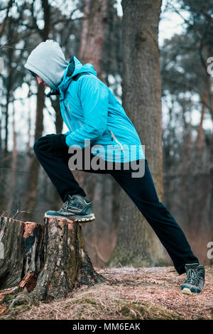 Jeune homme exerçant à l'extérieur dans une forêt entre les arbres sans feuilles sur gel froide journée d'automne. Boy est le port de vêtements de sport Banque D'Images