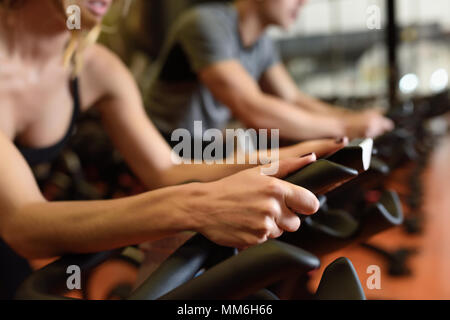 Deux personnes autour de la salle de sport, l'exercice de jambes faisant cardio vélo vélos. Dans un couple de spinning portant des vêtements de sport. Banque D'Images