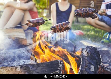 Les enfants bénéficient de camp. Les filles (famille) faire griller les saucisses sur le jardin. Banque D'Images