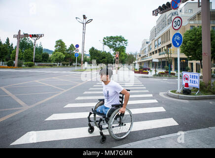 (180510) --, de BEICHUAN le 10 mai 2018 (Xinhua) -- un survivant, Haiyang Zheng qui a perdu ses jambes dans le 8.0-magnitude 2008 séisme de Wenchuan, déplace son fauteuil roulant de traverser la route dans le nouveau comté de Beichuan, le sud-ouest de la province chinoise du Sichuan, le 8 mai 2018. Il y a dix ans, Zheng, 17 ans, étudiant à l'École de Beichuan, a dégagé 22 heures après qu'il a été pris au piège dans les décombres du bâtiment de l'école dans le comté de Beichuan. A Beichuan l'un des plus durement touchés lorsque le séisme a frappé le Sichuan catastrophique du comté de Wenchuan le 12 mai 2008. Zheng a été un survivant du séisme qui Banque D'Images