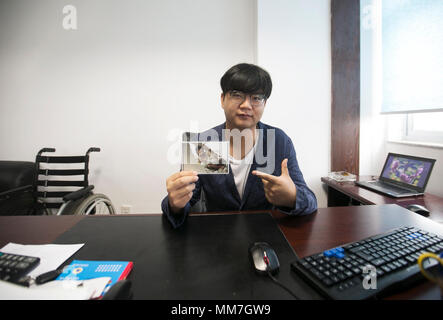 (180510) --, de BEICHUAN le 10 mai 2018 (Xinhua) -- un survivant, Haiyang Zheng qui a perdu ses jambes dans le 8.0-magnitude 2008 séisme de Wenchuan, montre sa photo en vertu de rocailles à son bureau dans le sud-ouest de la province chinoise du Sichuan, le 8 mai 2018. Il y a dix ans, Zheng, 17 ans, étudiant à l'École de Beichuan, a dégagé 22 heures après qu'il a été pris au piège dans les décombres du bâtiment de l'école dans le comté de Beichuan. A Beichuan l'un des plus durement touchés lorsque le séisme a frappé le Sichuan catastrophique du comté de Wenchuan le 12 mai 2008. Zheng a été un survivant du tremblement de terre qui a laissé plus de 80 Banque D'Images