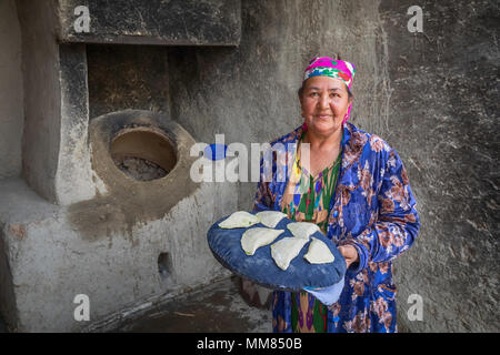 Boukhara, Ouzbékistan - 20 Avril 2018 : une femme âgée se prépare à mettre le samsa au tandoor - un four ouzbek traditionnel Banque D'Images