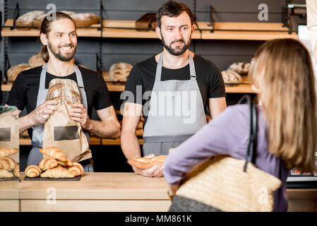 Femme acheter du pain dans la boulangerie avec l'homme ventes Banque D'Images