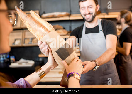 Femme acheter du pain dans la boulangerie avec l'homme ventes Banque D'Images