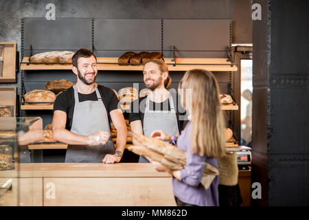 Femme acheter du pain dans la boulangerie avec l'homme ventes Banque D'Images