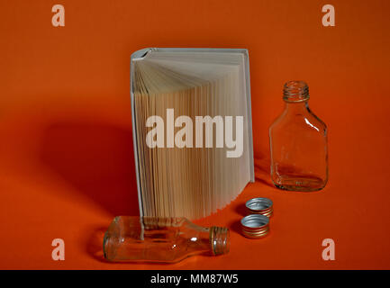 Les bouteilles d'alcool et de livre sur fond orange Banque D'Images