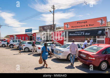 Un groupe de voitures se trouve à l'extérieur des entreprises locales comme les gens de l'usine de Guguletu township de Cape Town, Afrique du Sud Banque D'Images