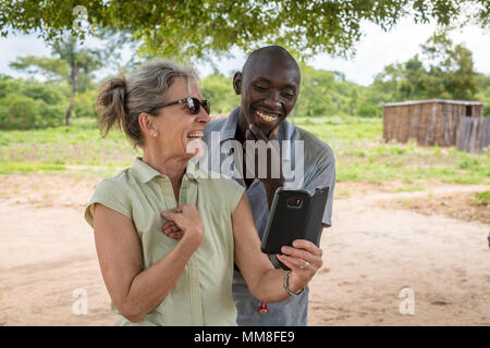 Une femme avec excitation partage quelque chose sur son téléphone avec un jeune homme à Livingstone, Zambie Banque D'Images
