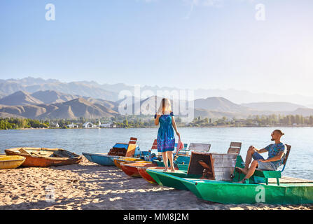 Couple heureux sur bateau vert de l'ancienne école sur la plage du lac Issyk Kul au Kirghizstan Banque D'Images