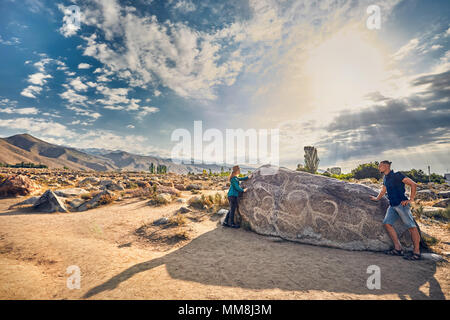 Chemise à carreaux en couple dans le musée en plein air près de stone ancient petroglyph de chèvres à Kirghizistan Banque D'Images