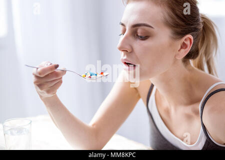 Sad young woman looking at the pills Banque D'Images