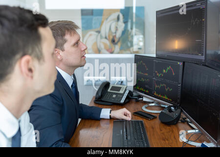 Les stocks commerciaux d'affaires en ligne. Les courtiers en regardant des graphiques, des index et des chiffres sur plusieurs écrans d'ordinateur. Collègues de discussion en trad Banque D'Images
