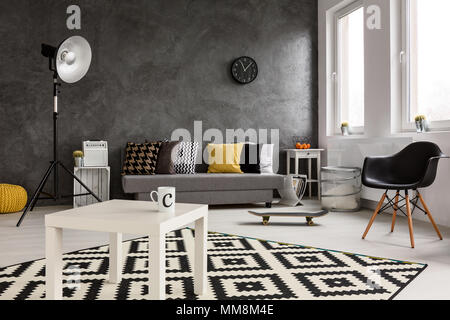 Chambre familiale spacieuse et moderne confortable. Au milieu de la table de café blanc avec tasse de gauche et du skateboard sur le plancher Banque D'Images