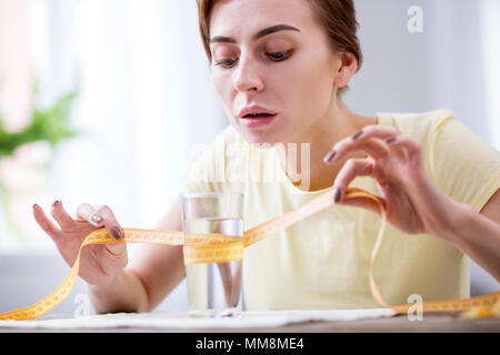 Belle jeune femme mesurant le verre Banque D'Images