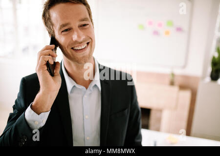 Smiling entrepreneur discuter affaires sur téléphone mobile. L'homme faisant affaires appels sur téléphone mobile. Banque D'Images