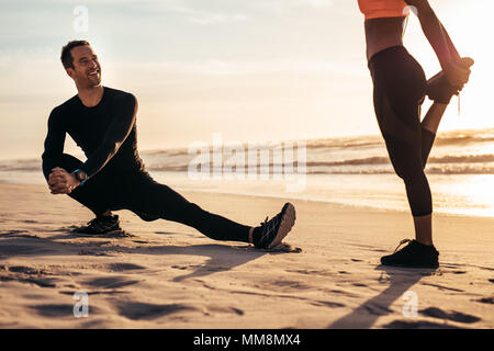 Les jeunes l'exercice sur la plage de matin. Runner stretching et réchauffe le long de la mer et d'avoir un chat. Banque D'Images