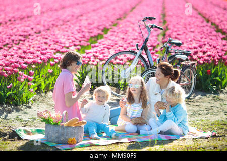 Pique-nique en famille à champs de fleurs tulipes en Hollande. Jeune mère et enfants de manger le déjeuner dans blooming tulipes fleur champ. Maman et les enfants voyagent en vélo. Banque D'Images