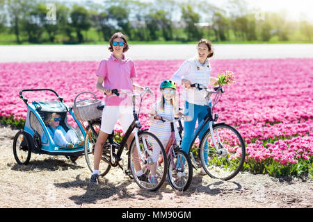 Heureux famille néerlandaise riding bicycle in tulip champs de fleurs en Hollande. Mère et enfants sur des vélos à la floraison des tulipes en Hollande. Bébé en vélo. Banque D'Images