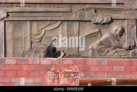 Pèlerin tibétain fait tourner un moulin à prières à l'extérieur de la Sainte Ecriture Imprimerie Bakong monastère à Dege, Sichuan, Chine Banque D'Images