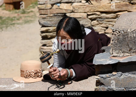 Pèlerin tibétain fait tourner un moulin à prières à l'extérieur de la Sainte Ecriture Imprimerie Bakong monastère à Dege, Sichuan, Chine Banque D'Images