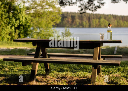 Une bouteille d'eau avec du citron et un verre. Un banc sur lequel est placée une boisson rafraîchissante. La saison de printemps. Banque D'Images