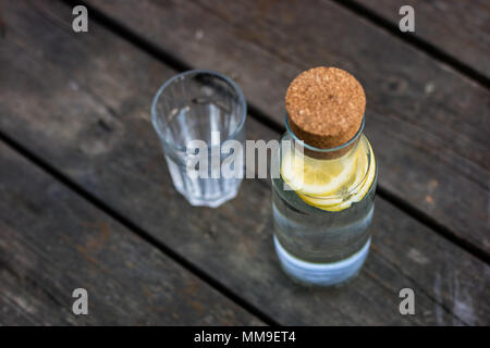 Une bouteille d'eau avec du citron et un verre. Un banc sur lequel est placée une boisson rafraîchissante. La saison de printemps. Banque D'Images