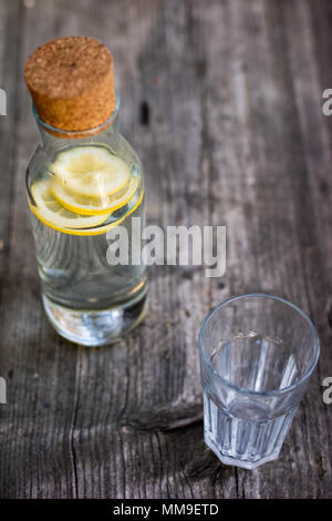 Une bouteille d'eau avec du citron et un verre. Un banc sur lequel est placée une boisson rafraîchissante. La saison de printemps. Banque D'Images