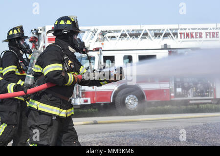 Deux états des équipes du 72e Escadron de génie civile, pompiers, travailler ensemble à l'approche de l'appareil de formation incendie de l'avion le 13 septembre 2017, Tinker Air Force Base, Texas. Les pompiers qui étaient en formation dans la recertification annuelle environnement réaliste. (U.S. Air Force photo/Greg L. Davis) Banque D'Images