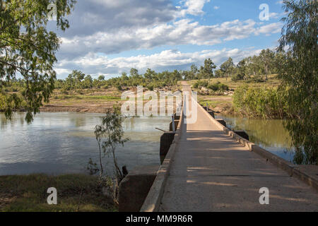 Basse longue traversée de pont en béton étroit des eaux calmes de la rivière Bowen avec de gravier menant sur dans le bush sous ciel bleu en Australie Qld Banque D'Images