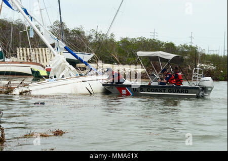 L'équipage de la Garde côtière canadienne avec les Florida Keys de la Direction générale de la fonction de soutien en cas d'urgence 10 Floride place une évaluation autocollant sur la coque d'un navire de personnes déplacées par le cyclone Irma dans Boot Key Harbour, près de Marathon, en Floride, le 29 septembre, 2017. Plus d'information est disponible pour les propriétaires de navire intéressé par la suppression de leur bateau à http://myfwc.com/boating/vessel-hotline/removal/. U.S. Coast Guard photo de Maître de 2e classe David Weydert. Banque D'Images