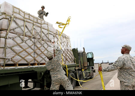 Soldats affectés à la compagnie de transport, 432e 346e, 166e bataillon de transport Groupe de soutien régional, 1ère Commande de soutien de mission, à Ceiba, Puerto Rico, sûr palettes de repas prêts-à-manger, et des bouteilles d'eau sur un système logistique véhicules avant de le distribuer à la Floride, Barceloneta, Hatillo et Quebradillas, Porto Rico, à l'Aero Puerto Luis Muñoz Marín International, un aéroport de San Juan, Porto Rico, le 30 septembre 2017. Le ministère de la Défense soutient l'Agence fédérale de gestion des urgences pour aider les personnes touchées par l'Ouragan Maria afin de minimiser la souffrance et dans le cadre Banque D'Images