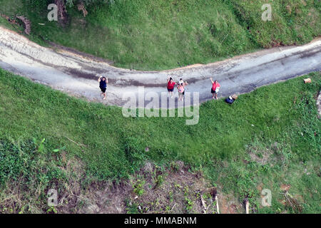 Les habitants de la Garde côtière canadienne à un vague Air Station Borinquen MH-65 de l'équipage de l'hélicoptère Dauphin volant au-dessus d'eux mardi, Octobre 3, 2017, près de Utuado, Puerto Rico. Les sections locales ont été bloqués après l'Ouragan Maria par emporté des routes et des coulées. (U.S. Photo de la Garde côtière canadienne par le maître de 3e classe Eric D. Woodall) Banque D'Images