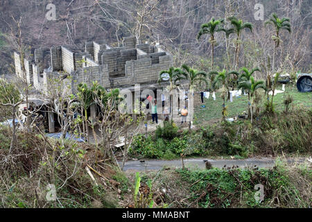 Les habitants de la Garde côtière canadienne à un vague Air Station Borinquen MH-65 de l'équipage de l'hélicoptère Dauphin volant au-dessus d'eux mardi, Octobre 3, 2017, près de Utuado, Puerto Rico. Les sections locales ont été bloqués après l'Ouragan Maria par emporté des routes et des coulées. (U.S. Photo de la Garde côtière canadienne par le maître de 3e classe Eric D. Woodall) Banque D'Images