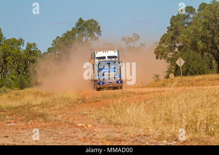 Camion semi-remorque qui se déplacent le long de la route de l'outback en nuage de poussière rouge près de Clermont dans l'ouest du Queensland en Australie Banque D'Images