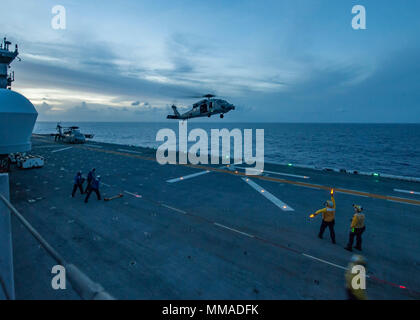 171003-N-JW440-0065 MER DES CARAÏBES (oct. 3, 2017) le signal des marins l'atterrissage d'un MH-60S Sea Hawk comme le navire d'assaut amphibie USS Wasp LHD (1) le transit de la mer des Caraïbes à l'appui de l'Ouragan Maria secours dans Puerto Rico. Le ministère de la Défense soutient l'Agence fédérale de gestion des urgences, le principal organisme fédéral, en aidant les personnes touchées par l'Ouragan Maria afin de minimiser la souffrance et est une composante de l'ensemble de l'intervention. (U.S. Photo par marine Spécialiste de la communication de masse 2e classe Rawad Madanat/libérés) Banque D'Images