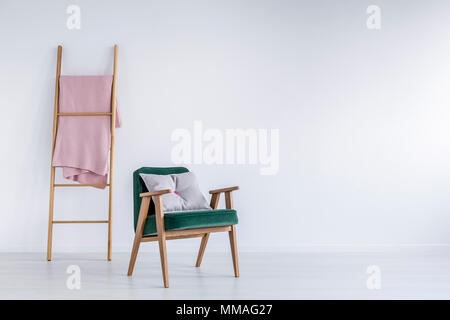 Chambre blanche avec échelle et élégant fauteuil vert Banque D'Images