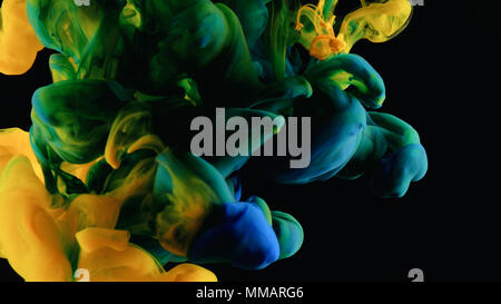 Rouge, jaune et bleu dans l'eau d'encre à grande vitesse de prise de vue appareil photo. peinture a chuté, de réagir, de créer des formations nuageuses abstrait et la métamorphose sur bl Banque D'Images