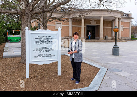 Une femme se trouve à côté du panneau de bienvenue au cimetière national d'Arlington Banque D'Images