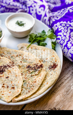 Cuisine traditionnelle d'Azerbaïdjan. Capture d qutabs verticale -pain plat avec les verts. Servi avec du yogourt dans la plaque en céramique blanche. Banque D'Images