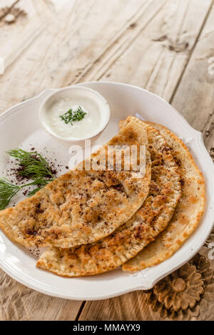 Cuisine traditionnelle d'Azerbaïdjan. Capture d qutabs verticale -pain plat avec la farcissure prг©parent. Servi avec du yogourt dans une grande plaque en céramique. Banque D'Images