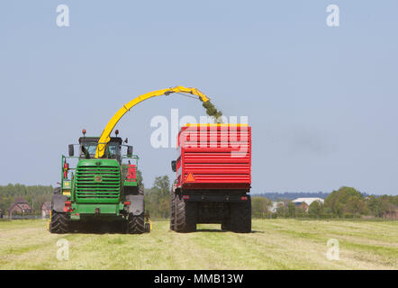 Les charges du tracteur sur l'herbe fraîchement tondue meadow journée ensoleillée en été sous ciel bluw Banque D'Images