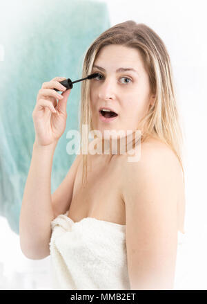 Portrait de jeune femme étonné avec la bouche ouverte de faire un miroir dans la salle de bains Banque D'Images