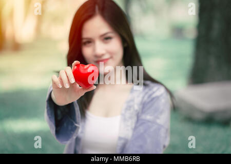 Donner de l'amour ensemble concept : Cute Asian woman hold coeur rouge pour aimer partager belle nuance de couleur vintage Banque D'Images
