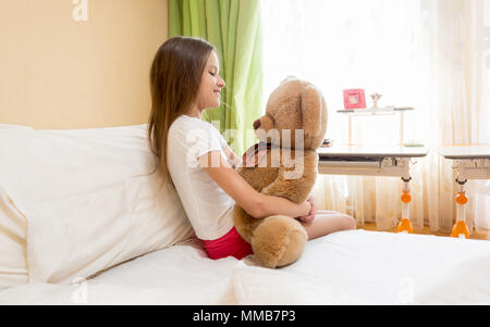 Portrait of cute teenage girl sitting in bed and teddy bear Banque D'Images