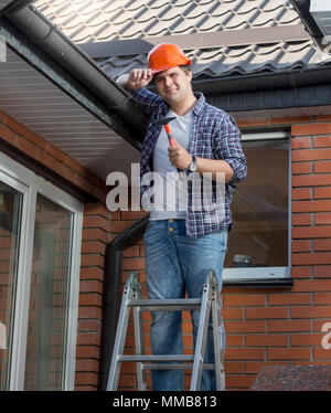 Portrait of smiling carpenter in hardhat debout sur l'escabeau Banque D'Images