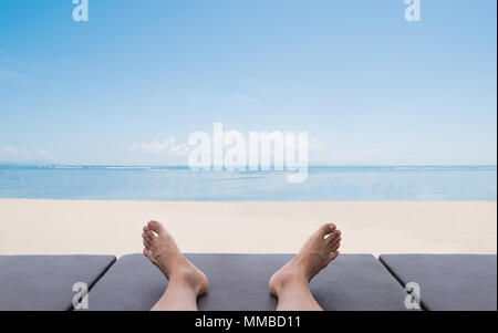 Des vacances d'été et de vacances. a man relaxing on lounge chair bronzer sur la plage en été Banque D'Images