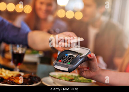 Groupe d'Amis de payer pour repas au restaurant Banque D'Images