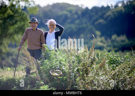 Mari et femme, un homme âgé portant un chapeau et à l'aide de bâton de marche et de vieille femme marchant le long chemin. Banque D'Images